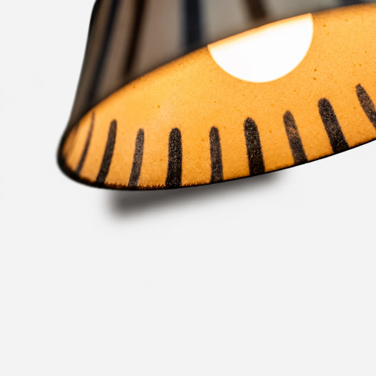 Warm light glowing through the striped ceramic shade interior